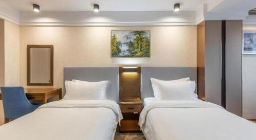 a hotel room with two beds and a blue chair at Dalian Bohai Pearl Hotel in Dalian