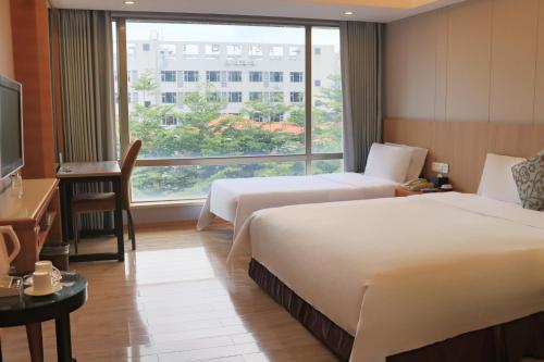 a hotel room with two beds and a large window at Dongguan Well Garden Hotel in Dongguan