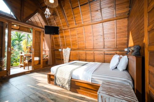 a bedroom with a bed in a wooden room at Ubud Leke Leke Guest House in Tegalalang