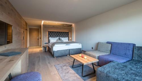 sypialnia z łóżkiem, kanapą i stołem w obiekcie Hotel Madonna w mieście Castelrotto