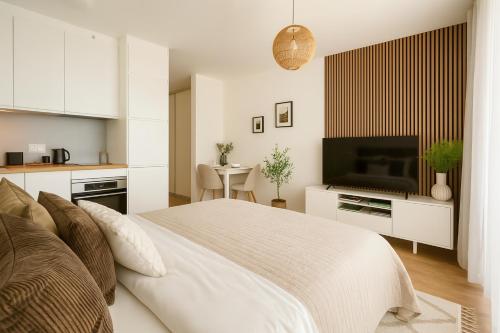 a white bedroom with a bed and a television at nook I Airport apartments in Bratislava