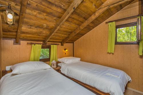 two beds in a room with green curtains at Treehouse Dubrovnik in Čilipi