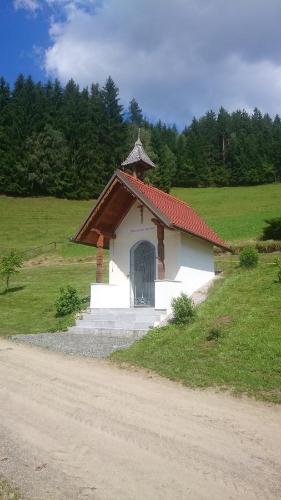 a small chapel in a field next to a dirt road at BIO-Peisingerhof in Sankt Stefan ob Leoben