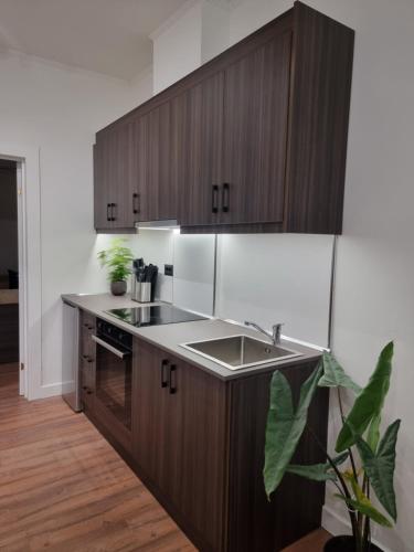 a kitchen with wooden cabinets and a sink at KC Apartments 3 in Berat
