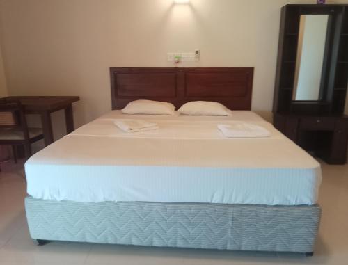 Un dormitorio con una cama grande con cabecero de madera. en Albergo Marina Nilwella, en Dikwella