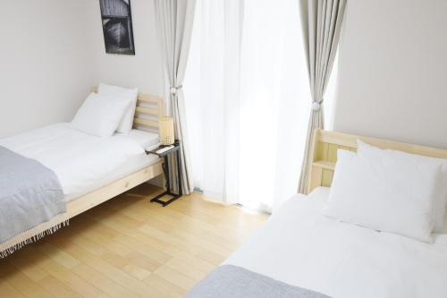 a bedroom with two beds and a window at Dori Dori House Shinjuku1 in Tokyo