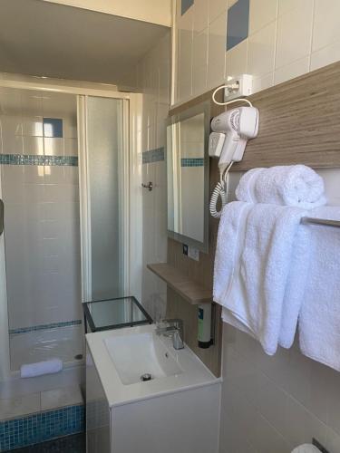 a bathroom with a sink and a shower and towels at Logis Hôtel Villa Victorine in Nice