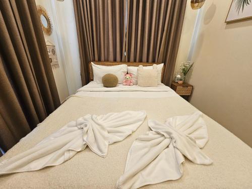 a bed with white sheets and a teddy bear on it at Nordika Hill in Pak Chong