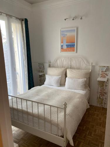 a bedroom with a white bed with pillows and a window at Logis Hôtel Villa Victorine in Nice