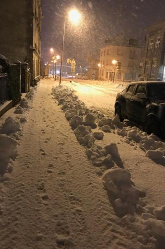 a snow covered street at night with a car parked at Maison spacieuse au bord d'un étang et face à la nature in Ban-sur-Meurthe-Clefcy