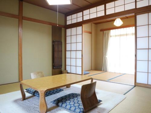 a dining room with a wooden table and chairs at Yumorinoyado Sannozyou in Mogami