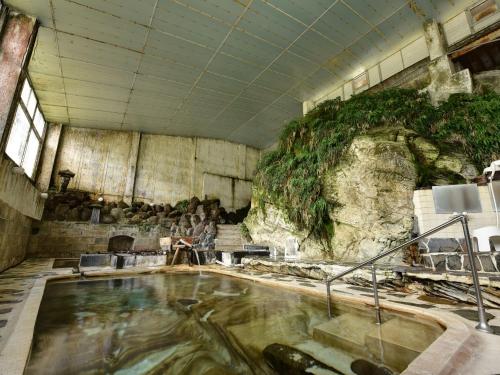 a bath room with a large pool of water at Yumorinoyado Sannozyou in Mogami
