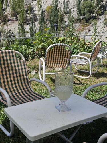 three chairs and a table with a vase on it at Escape Hostel in Karimabad Hunza