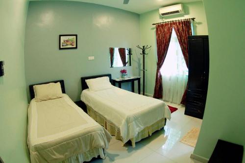 a bedroom with two beds and a window at Twin Castle Homestay Kuala Pilah in Kuala Pilah
