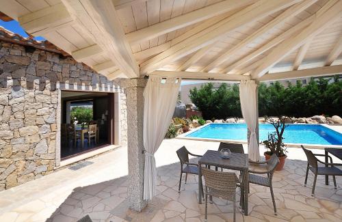 a pavilion with a table and chairs next to a pool at B&B I Graniti Sardi in Villasimius