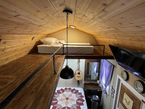 a small room with a bed and a guitar at Tiny Tiny Bunkhouse in Cane Beds