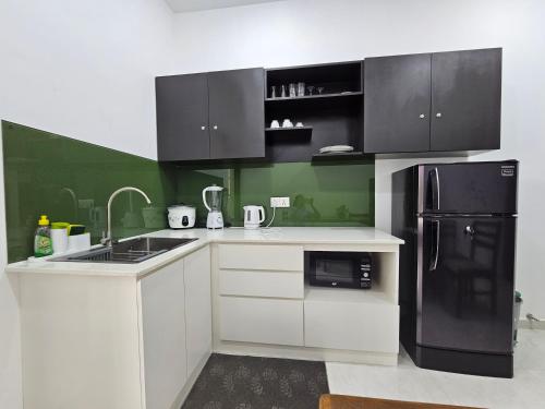 a kitchen with white cabinets and a black refrigerator at Green Vibe Apartments in Nugegoda