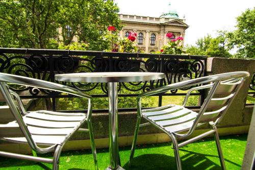 two chairs and a table in front of a fence at Apartments Legacy in Belgrade