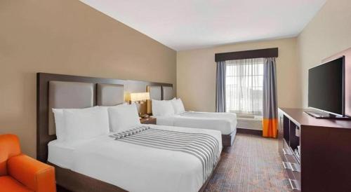 a hotel room with two beds and a flat screen tv at Best Western Plus Executive Inn in Toronto