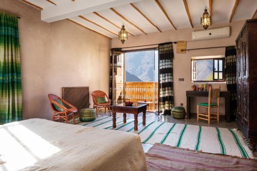 a bedroom with a bed and a desk and chairs at Le Village du Toubkal in Imlil