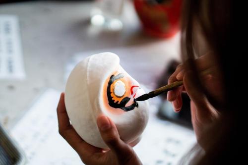 a woman painting a clown egg with a paintbrush at Four Seasons Hotel Osaka in Osaka