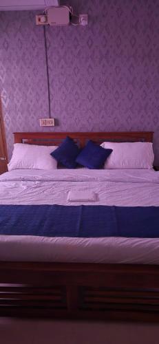 a bed with blue pillows in a purple bedroom at Brundhavan - Peaceful villa in Kottayam in Kottayam
