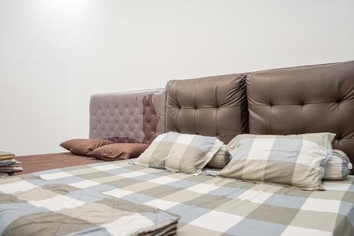 a bed with a leather headboard and pillows at Griya Mahoni Palagan Homestay Jogja in Ngaglik