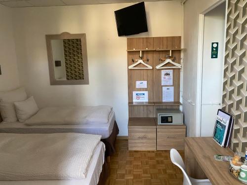a room with two beds and a desk and a tv at Logis Hôtel Villa Victorine in Nice