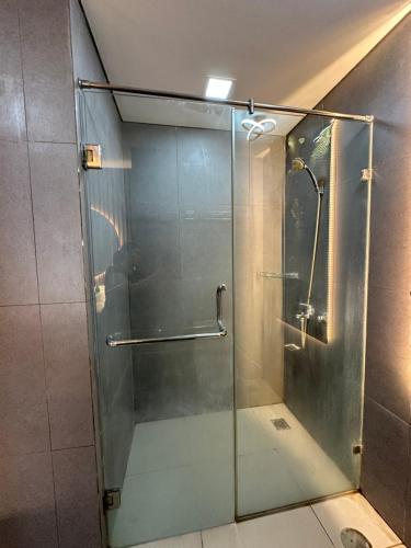 a shower with a glass door in a bathroom at Asha suite by Patraland Amarta Apartemen in Kejayan