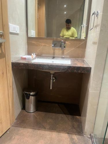 a man taking a picture of a bathroom sink at Nirvana Grand Hotel & Resort in Gaya