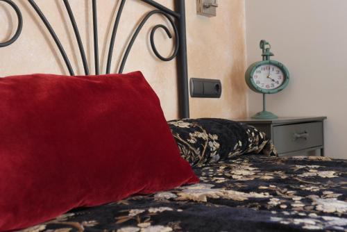 a bed with a red pillow and a clock on the wall at Hotel Restaurant El Bosc in Banyeres del Penedes