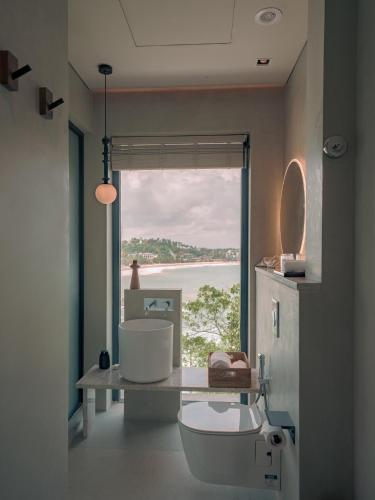 a bathroom with a view of the ocean through a window at NiiRA in Mirissa