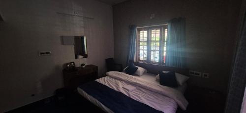 a bedroom with a bed and a window at Brundhavan - Peaceful villa in Kottayam in Kottayam