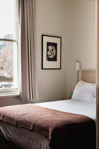 a bedroom with a bed and a window at Naughtons Hotel in Melbourne