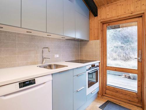 una cucina con mobili bianchi, un lavandino e una finestra di Tranquil Beach Retreat - By Traum Ferienwohnungen a Skagen