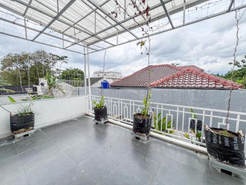 a balcony with potted plants and a white fence at Griya Mahoni Palagan Homestay Jogja in Ngaglik