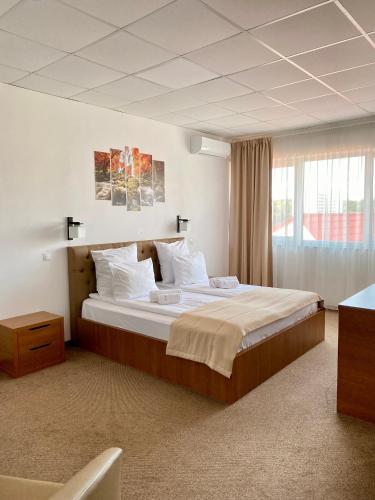 a bedroom with a large bed with white sheets at Pensiunea Tulip in Baile Felix