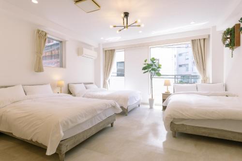 a white bedroom with three beds and a window at 8min walk from Shibuya Sta in Tokyo