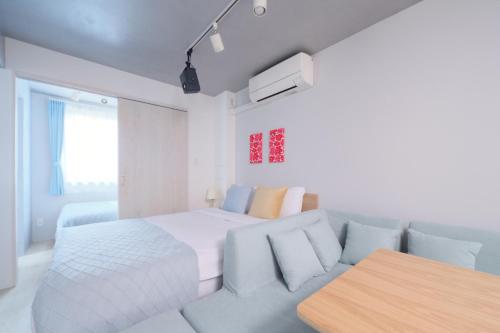 a white bedroom with a bed and a couch at Monzen-nakacho 1LDK with projector, 2 double beds,301 in Tokyo
