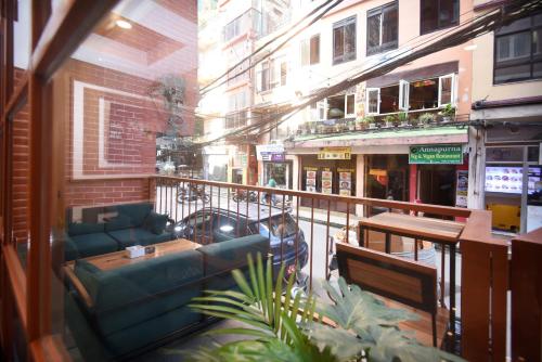 a balcony with a couch and tables on a city street at Hotel Cozy Heaven in Kathmandu