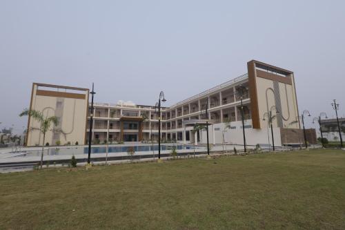 a large building with a grass field in front of it at Nirvana Grand Hotel & Resort in Gaya