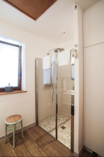a shower with a glass door and a stool in a bathroom at La vie de château 2 in La Celle-sous-Gouzon