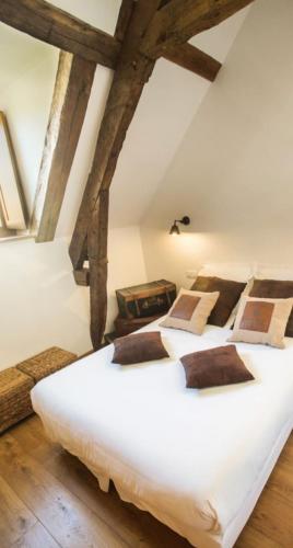 a large white bed in a room with beams at La vie de château 2 in La Celle-sous-Gouzon