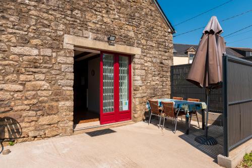 a brick building with a red door and a table and an umbrella at Gîte à la ferme de Questembert in Questembert