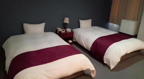 two beds in a hotel room withskirts at AKISAWA HOTEL in Shimanto