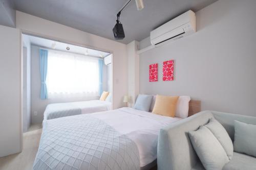 a white bedroom with a bed and a couch at Monzen-nakacho 1LDK with projector, 2 double beds,301 in Tokyo