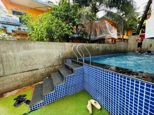 a swimming pool with a blue tile floor and stairs in it at Harsh angel holiday homes in Calangute
