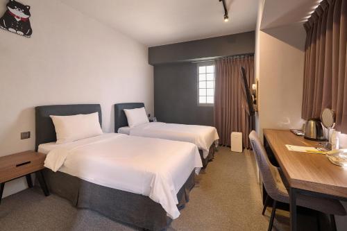 a hotel room with two beds and a desk at Doudian DDiNN Hotel in Taichung