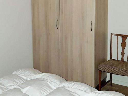 a bed with white sheets and a wooden cabinet at 8 person holiday home in Sydals in Mommark