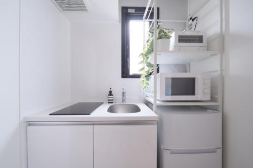 a white kitchen with a sink and a microwave at Monzen-nakacho 1LDK with projector, 2 double beds,301 in Tokyo